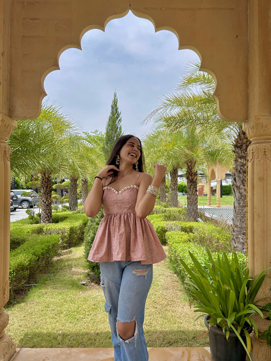 Soft pink printed peplum top with sweetheart neckline and shell detailing.